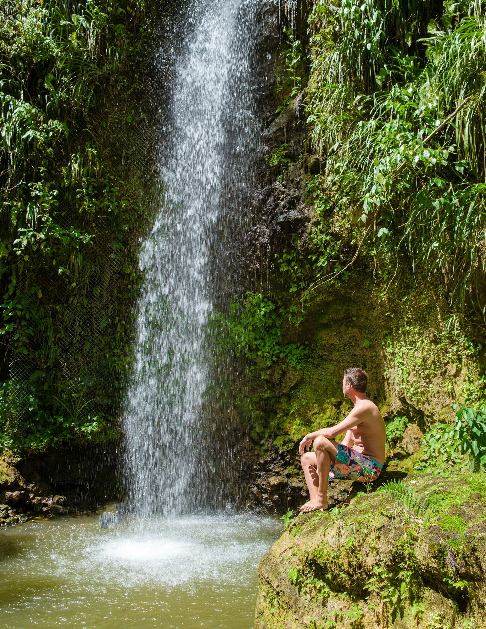 Young men relaxing at Toraille waterfall St Lucia. Saint Lucia jungle waterfall and men swimming